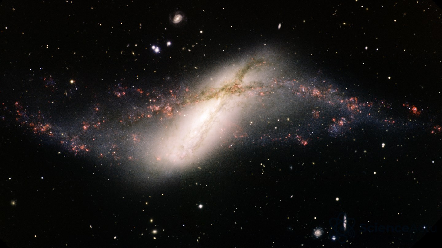 Image télescopique d'une galaxie allongée et brillante dotée d'un noyau central lumineux, encerclée par un anneau déformé d'étoiles et de gaz, sur un fond constellé d'étoiles et de galaxies.