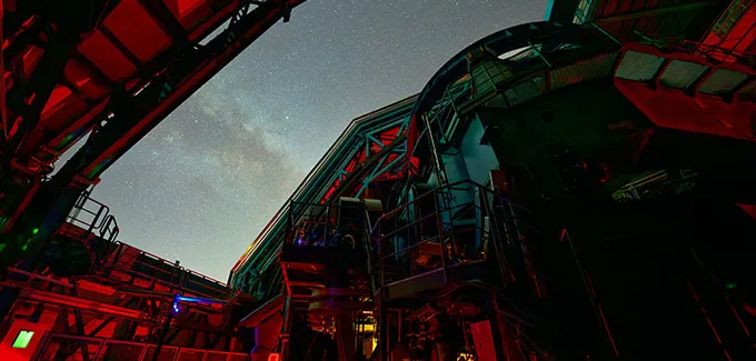 Vue nocturne de la coupole de l'observatoire Vera Rubin ouverte sous un ciel étoilé.