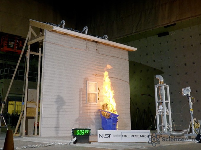 Poubelle à côté d'une maquette de maison en feu lors d'un test