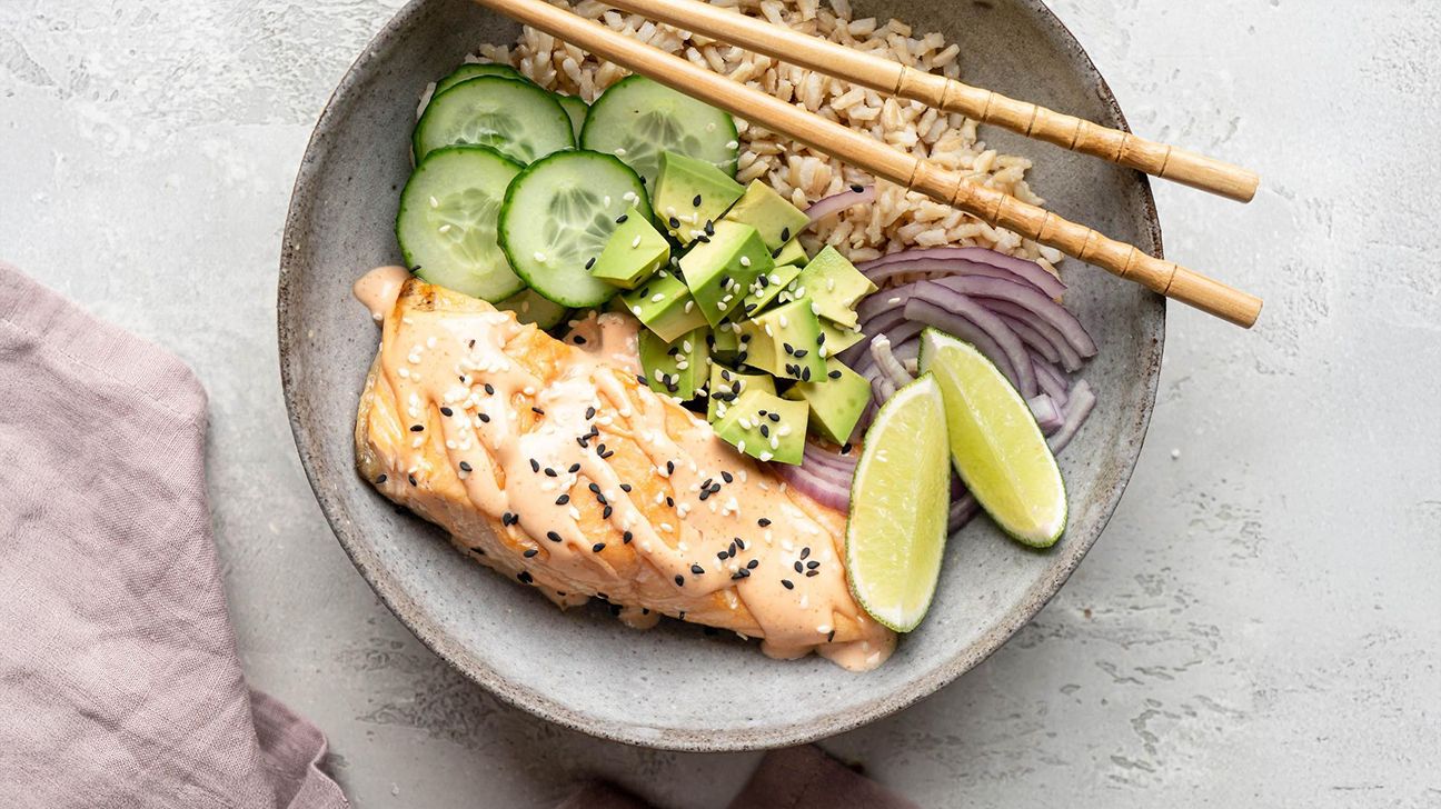 Bol épicé de saumon avec de l'avocat, du concombre, des oignons et une sauce soja