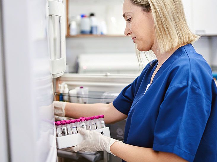 Une professionnelle de santé rangeant des stylos injecteurs de médicaments biologiques dans un réfrigérateur médicalisé.