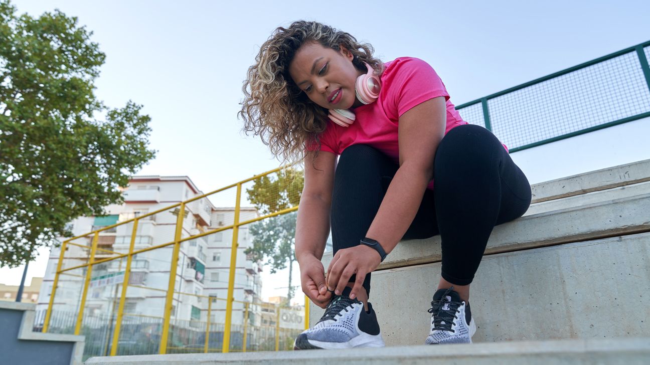 Femme laçant ses chaussures de course en extérieur, se préparant pour un jogging