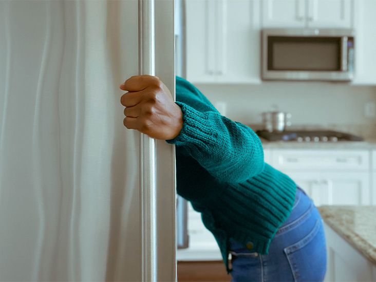 Une personne ouvre la porte d'un réfrigérateur pour y chercher ou y ranger un médicament sensible aux variations thermiques.