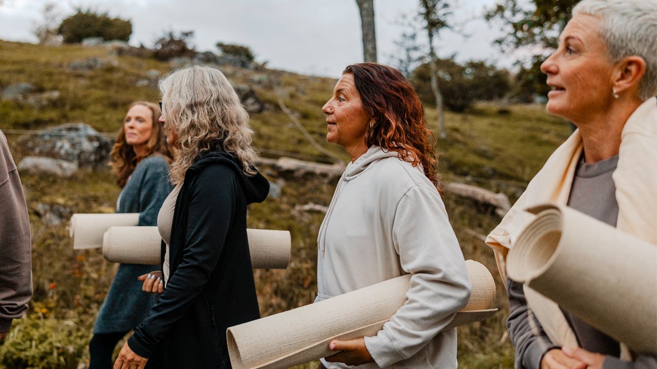 Femmes matures marchant à l'extérieur avec des tapis de yoga, illustrant la santé active pendant la transition ménopausique