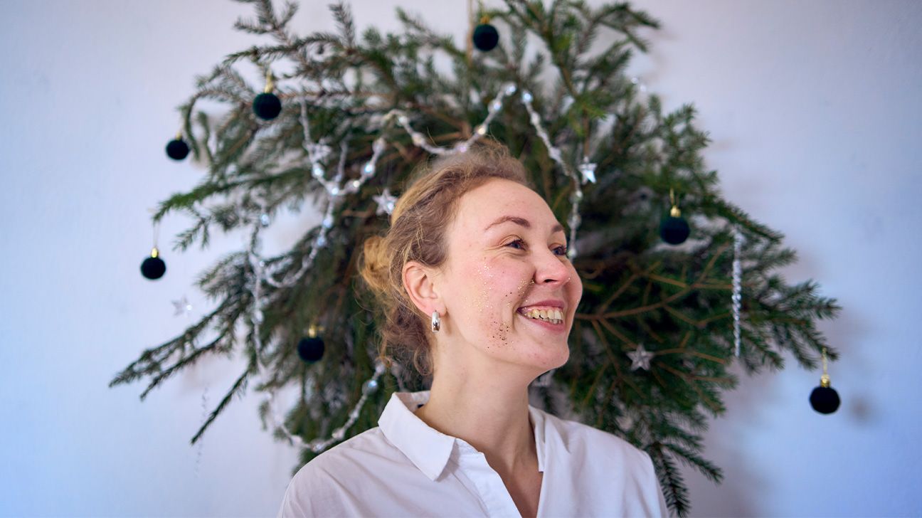 Femme souriante devant une couronne de Noël, illustrant la gestion de l'hyperstimulation sociale