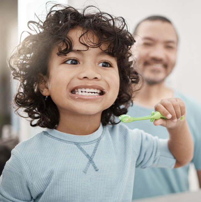 Enfant se brossant les dents avec l'aide d'un adulte