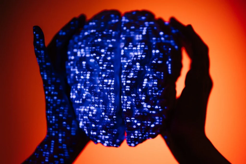 Deux mains entourent une forme de cerveau couverte de chiffres bleus sur un fond orange.